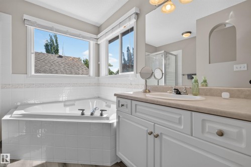 Corner soaking tub with tile surround, framed by multiple windows - 2327 37B Avenue, Edmonton, AB 