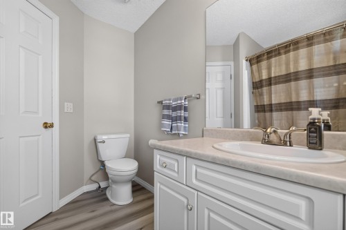 Bathroom featuring a white vanity with paneling, an integrated sink, and a large wall-mounted mirror - 2327 37B Avenue, Edmonton, AB 