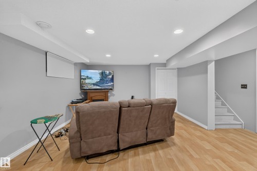 Spacious room featuring wood-finish flooring, recessed lighting, light gray walls, and white trim - 2327 37B Avenue, Edmonton, AB 