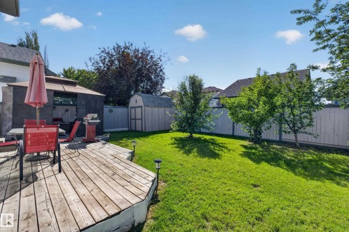 Expansive backyard featuring a large wooden deck, vibrant green lawn, and a privacy fence - 2327 37B Avenue, Edmonton, AB 