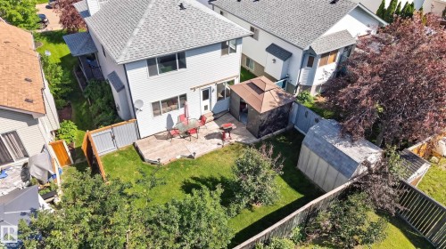 Spacious backyard featuring a concrete patio, a detached storage shed, perimeter fencing, and mature trees - 2327 37B Avenue, Edmonton, AB 