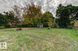 Expansive lawn area offering a garden shed, mature trees, and perimeter fencing - 