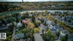Residential area featuring numerous homes with varied architectural styles, mature trees, and a prominent river bordering a forested landscape - 
