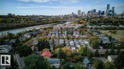 Residential area featuring a mix of housing styles, abundant mature trees, a prominent river, and a distant urban skyline - 