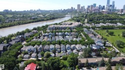 Aerial perspective showcasing a residential area with varied housing styles, mature trees, and a prominent riverfront - 