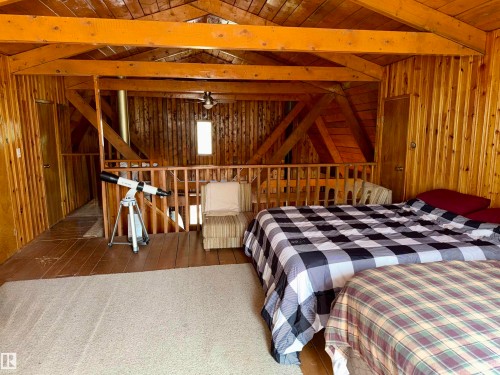 Wood-paneled room featuring an exposed beam ceiling, natural wood flooring - 208 60118 Secondary Highway 867, Rural St. Paul County, AB - Indoor Photo Showing Bedroom