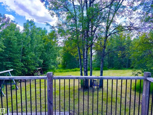 Private outdoor space featuring wood and metal railings, a natural grass area, and mature trees - 208 60118 Secondary Highway 867, Rural St. Paul County, AB - Outdoor