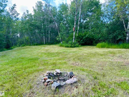 Expansive green space featuring a natural rock fire pit, surrounded by mature deciduous trees - 208 60118 Secondary Highway 867, Rural St. Paul County, AB - Outdoor
