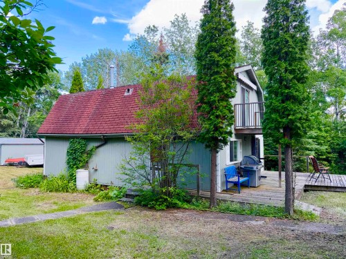 Cabin featuring a red shingle roof, light-colored siding, and a second-story balcony with metal railings - 208 60118 Secondary Highway 867, Rural St. Paul County, AB - Outdoor