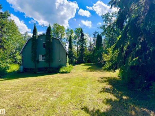 Barn-style Cabin with green siding, surrounded by mature trees - 208 60118 Secondary Highway 867, Rural St. Paul County, AB - Outdoor