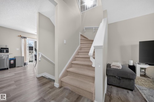 Carpeted staircase with white railing leading to an upper level - 59 2503 24 Street, Edmonton, AB 