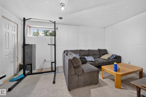 Finished basement area featuring a light-colored carpet, a window, and a white paneled door - 59 2503 24 Street, Edmonton, AB 