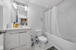 Bathroom featuring a white vanity with integrated sink, rectangular mirror, and wall-mounted light fixture - 