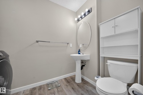 Pedestal sink with an oval mirror and a four-bulb vanity light fixture - 59 2503 24 Street, Edmonton, AB 