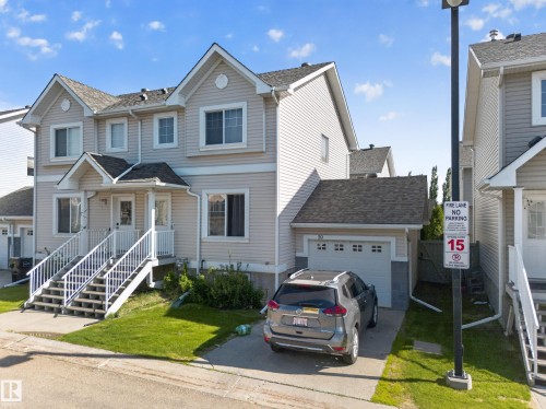 Contemporary townhome with light-toned siding and a prominent attached single-car garage - 59 2503 24 Street, Edmonton, AB 