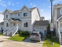 Contemporary townhome with light-toned siding and a prominent attached single-car garage - 59 2503 24 Street, Edmonton, AB 