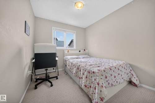 Room featuring neutral wall tones, carpet flooring, a window with exterior residential structures visible, and an overhead flush-mount light fixture - 59 2503 24 Street, Edmonton, AB 