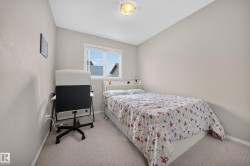 Room featuring neutral wall tones, carpet flooring, a window with exterior residential structures visible, and an overhead flush-mount light fixture - 