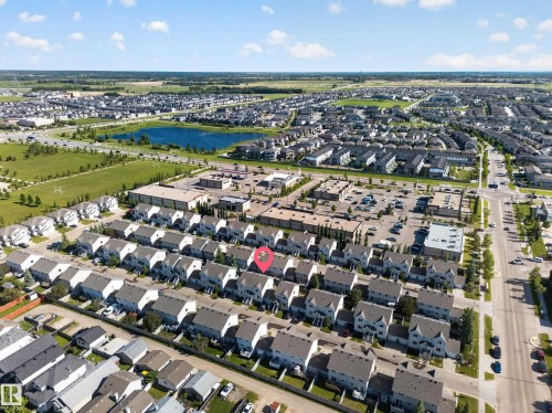 Aerial perspective showcasing a residential development with a prominent blue retention pond - 59 2503 24 Street, Edmonton, AB 