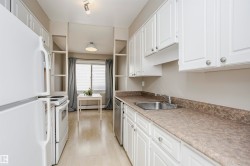 Kitchen featuring white cabinetry, light wood-finish flooring, a stainless steel sink, a full-size white refrigerator, and an electric range - 