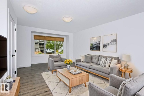 Living area featuring a large window with natural fiber blinds, recessed ceiling lighting, and wood-finish flooring - 27 4205 30 Street, Edmonton, AB 
