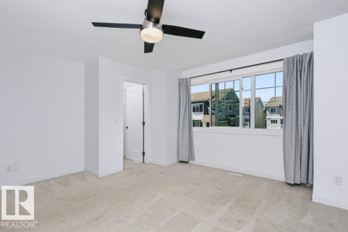 Carpeted room with a multi-pane window, white walls, and a modern ceiling fan with lighting - 27 4205 30 Street, Edmonton, AB 