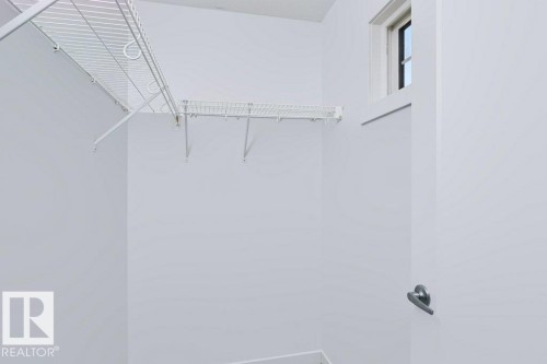 Walk-in closet featuring white wire shelving, white painted walls, and a single window with white trim - 27 4205 30 Street, Edmonton, AB 