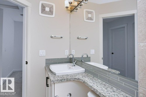 Bathroom vanity featuring a granite countertop, undermount sink, and a full-width mirror - 27 4205 30 Street, Edmonton, AB 