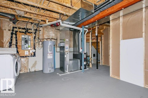 Utility room featuring exposed ceiling joists, a water heater, furnace, and electrical panel - 27 4205 30 Street, Edmonton, AB 