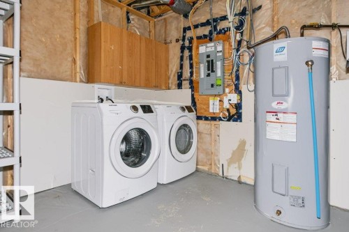 Utility space featuring a water heater, electrical panel, and wood-finish cabinetry - 27 4205 30 Street, Edmonton, AB 