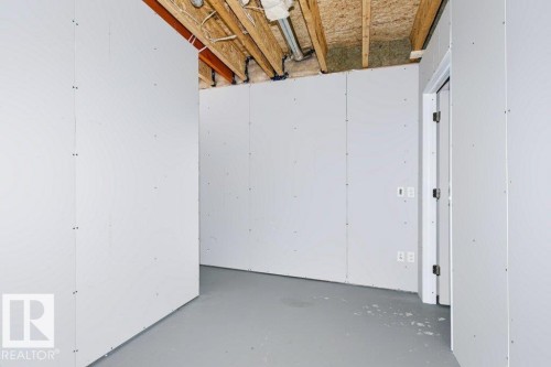 Unfinished interior space featuring exposed wooden ceiling joists, visible insulation, and light gray drywall walls - 27 4205 30 Street, Edmonton, AB 