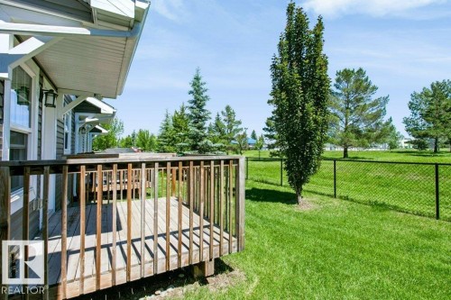 Expansive outdoor deck with wood railing, offering access to a spacious lawn - 27 4205 30 Street, Edmonton, AB 