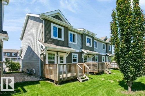 Rear exterior featuring multi-toned siding, individual wooden decks, and manicured lawns - 27 4205 30 Street, Edmonton, AB 