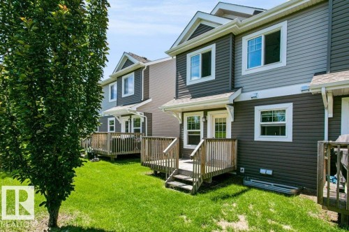 Multi-level exterior featuring dark gray and light gray siding, white trim, and a wood deck - 27 4205 30 Street, Edmonton, AB 