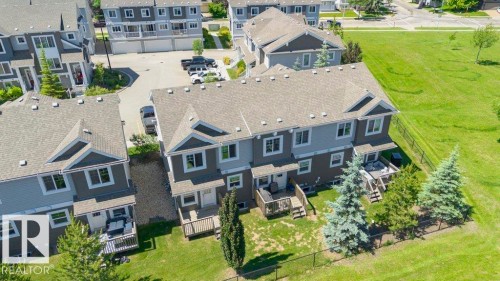 Rear exterior of a multi-unit property featuring individual wood decks and fenced yard spaces - 27 4205 30 Street, Edmonton, AB 