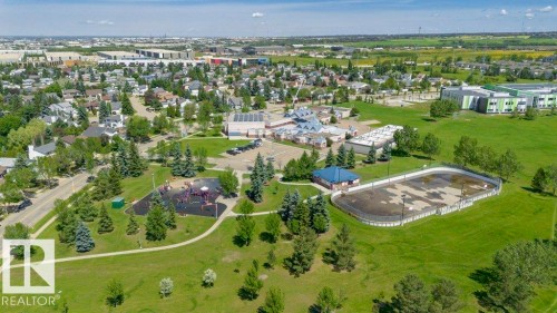 Expansive park area featuring a playground, mature trees, open green spaces, and a recreational rink - 27 4205 30 Street, Edmonton, AB 