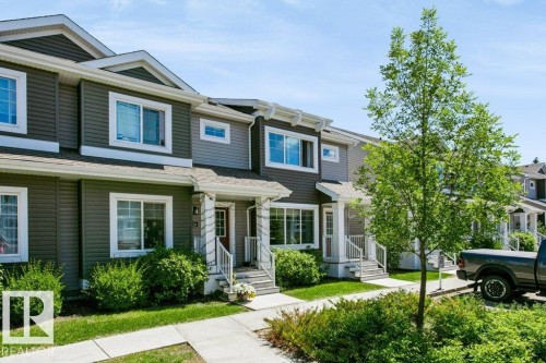 Townhome exterior featuring horizontal siding in a two-tone color scheme, white trim, gabled rooflines, and a covered front entry - 27 4205 30 Street, Edmonton, AB 