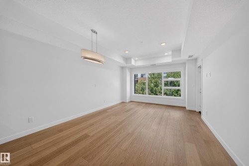 Spacious room featuring wood-finish flooring, white walls, and a large window - Sherwood Park, AB 