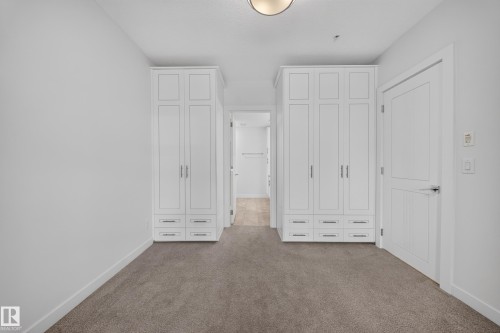 Light gray carpeting with two white built-in storage units featuring shaker-style doors and multiple drawers - Sherwood Park, AB 