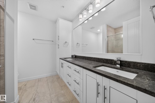 Dual vanity with dark patterned countertop and undermount sinks, illuminated by a multi-bulb fixture - Sherwood Park, AB 