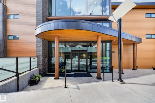 Modern building entrance featuring wood-finish siding, dark brick accents, and large glass doors - Sherwood Park, AB 