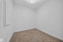 Carpeted room featuring white walls, white baseboards, a flush-mount ceiling light fixture, and an interior wall panel - Sherwood Park, AB 