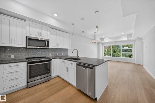 Modern kitchen featuring white cabinetry, dark countertops, and stainless steel appliances - Sherwood Park, AB 