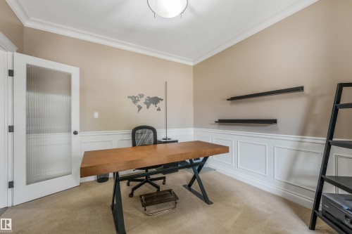Carpeted room featuring wainscoting, crown molding, and a door with a reeded glass panel - 1231 Tredger Crest, Edmonton, AB 