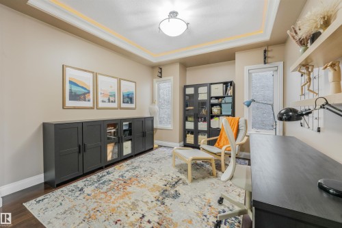 Recessed tray ceiling with crown molding, dark wood-finish flooring, and light beige wall tones - 1231 Tredger Crest, Edmonton, AB 