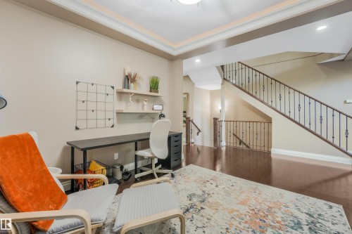 Interior space featuring wood-finish flooring, a two-story staircase with wrought iron balusters, recessed lighting, crown molding, and wall shelving - 1231 Tredger Crest, Edmonton, AB 