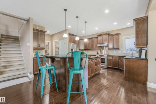 Spacious kitchen featuring rich wood cabinetry, dark countertops, stainless steel appliances, and wood-finish flooring - 1231 Tredger Crest, Edmonton, AB 