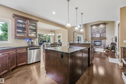 Open-concept kitchen featuring dark wood cabinetry, stainless steel dishwasher, and a center island with pendant lighting - 1231 Tredger Crest, Edmonton, AB 