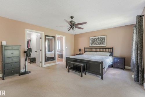 Spacious bedroom featuring neutral carpeting, a ceiling fan, and architectural openings to an adjoining closet and room - 1231 Tredger Crest, Edmonton, AB 