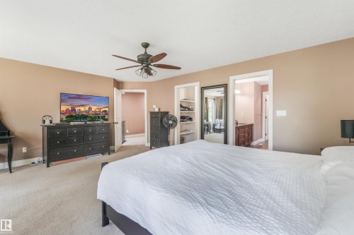 Carpeted interior space featuring a ceiling fan with integrated lighting, two open doorways, and a built-in shelving unit - 1231 Tredger Crest, Edmonton, AB 